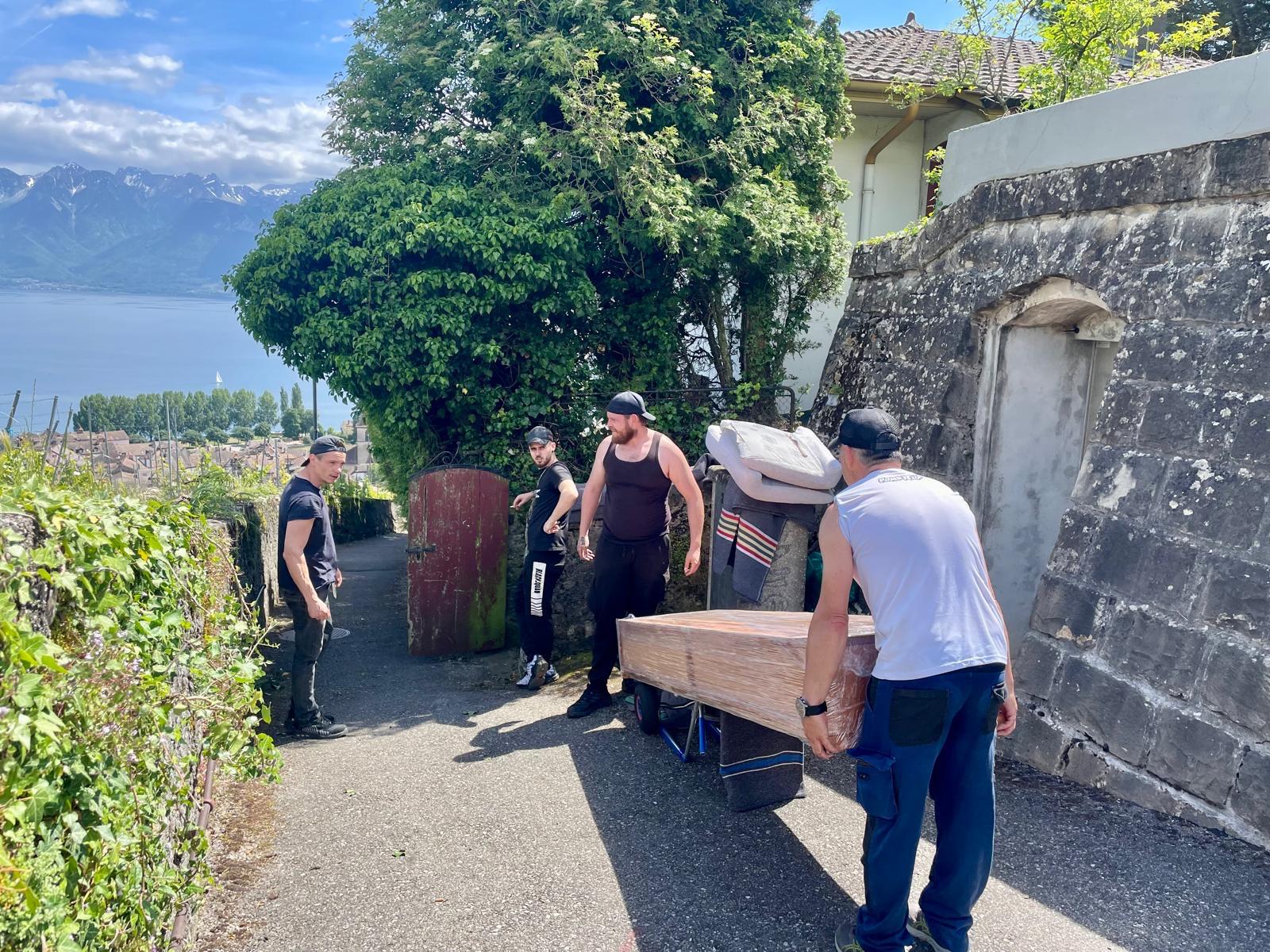 Équipe Moser déménageant un piano avec vue sur le lac Léman